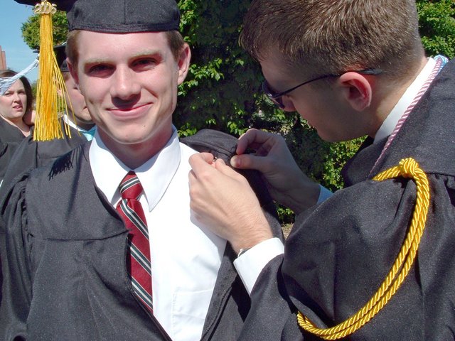 Steven Wilco helps Matt Schaefer with his CC medallion outside the Union before baccalaureate