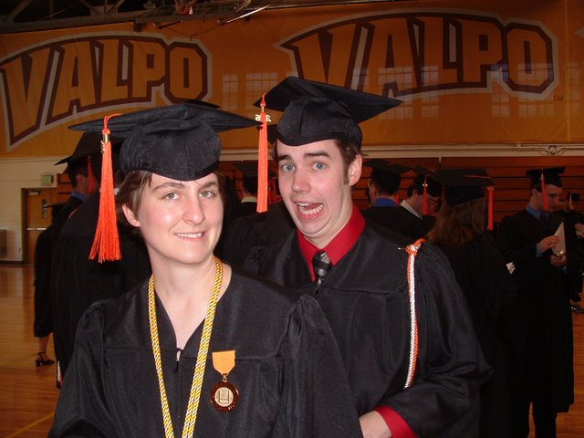 In a gym in the Athletics and Recreation Center before commencement:  Eric Spaeth making a funny face behind Kimberly Christman.