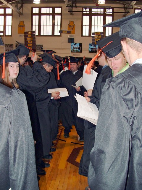 Engineers line up in a gym in the Athletics and Recreation Center in preparation for commencement.  The portion of the line pictured is the mechanical engineer part.  Several classmates are facing the camera (e.g., Christiana Johnson, Matthew Gierke, and Kyle Jones).