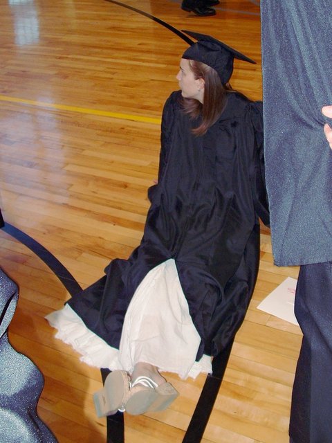 Before commencement, Erin Swanson sits on the floor of a gym in the Athletics and Recreation Center with her body facing the camera but her face profiled.
