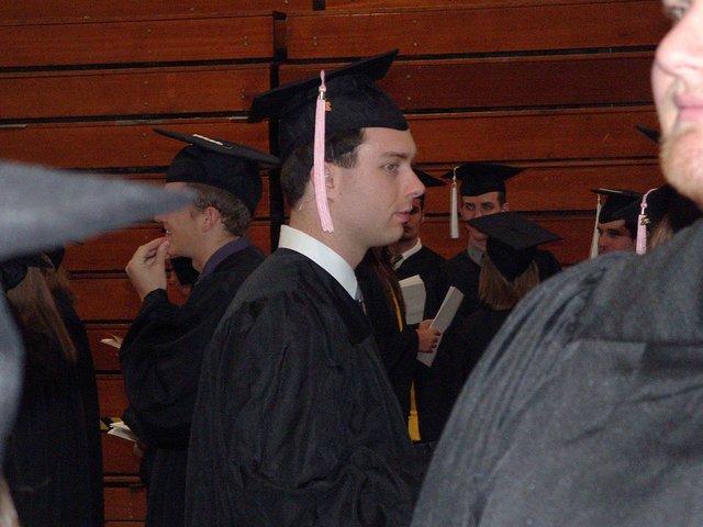 Carl Bear, viewed from profile, waits in line in a Athletics and Recreation Center gym before commencement.