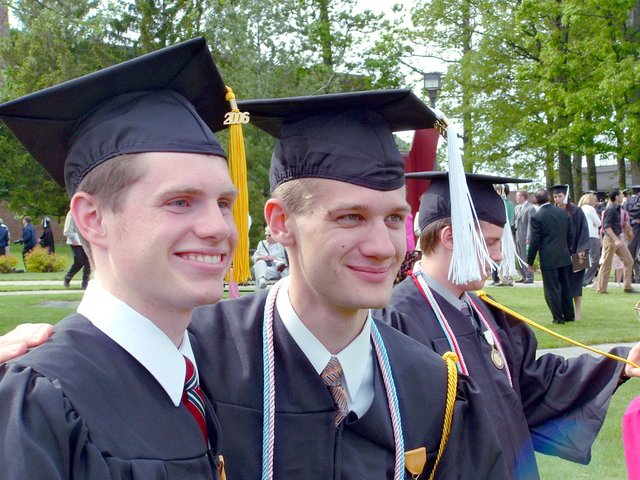 Matthew Schaefer and Steven Wilco pose in profile east of the Athletics and Recreation Center after commencement.  John Unrath is visible in the background.
